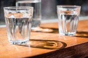 hree clear water glasses on a brown table; image by Jana Sabeth, via Unsplash.com.
