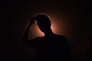 Silhouette image of man touching his head; image by Smit Patel, via Unsplash.com.