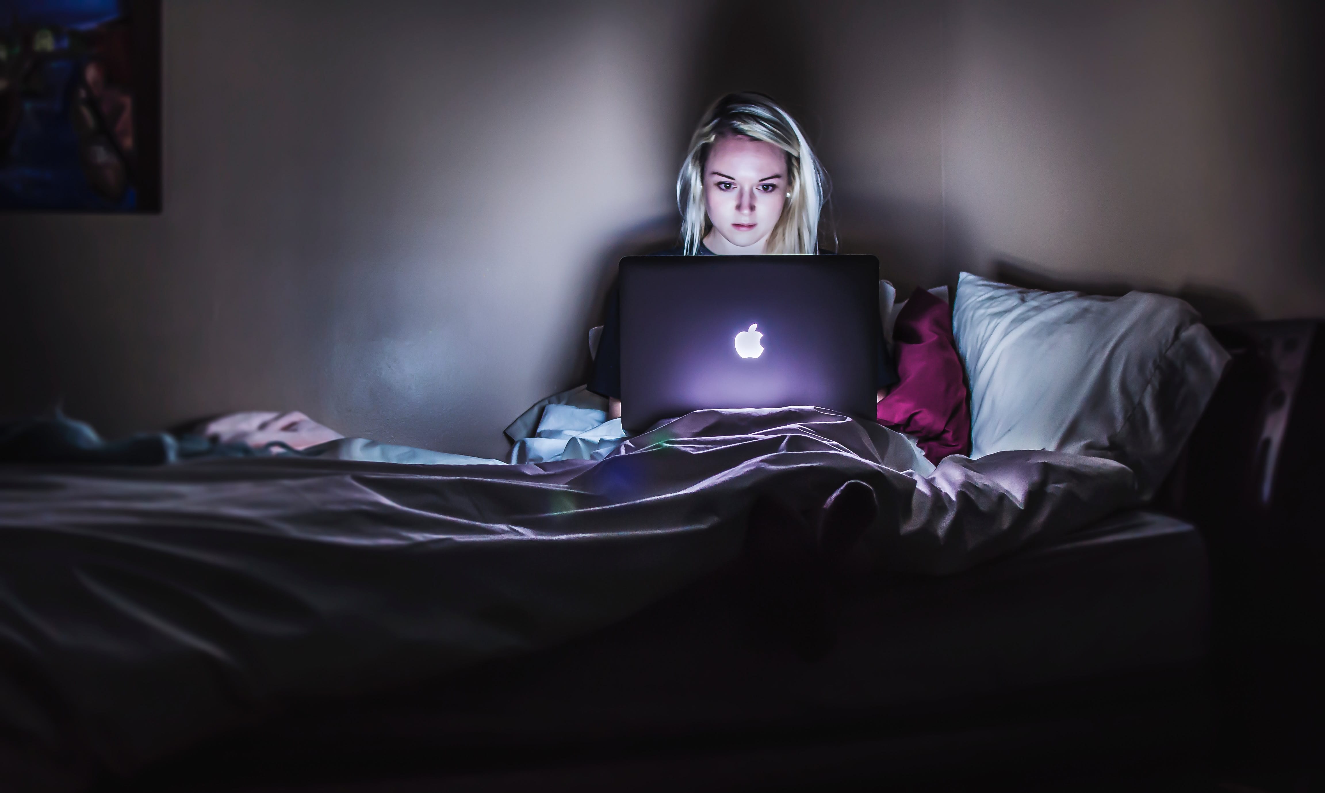 Woman using MacBook in bed; image by Victoria Heath, via Unsplash.com.