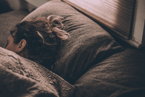 Woman sleeping in bed with all brown linens; image by Gregory Pappas, via Unsplash.com.