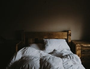 White bed comforter set and brown wooden bed frame beside brown wooden nightstand; image by Annie Spratt, via Unsplash.com.
