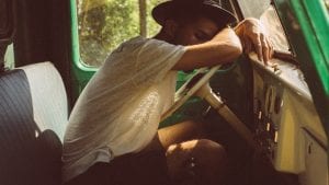 Man resting his arms and head on steering wheel of car; image by Lechon Kirb, via Unsplash.com.