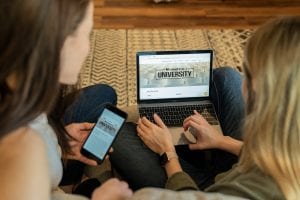 Woman using laptop sitting beside woman holding smartphone; image by Mometrix Test Prep, via Unsplash.com.