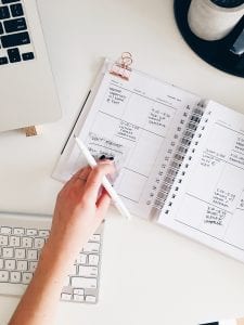 Woman with paper planner and pen; image by STIL, via Unsplash.com.