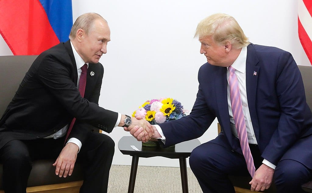 President Trump and Russian President Putin, seated, shaking hands.