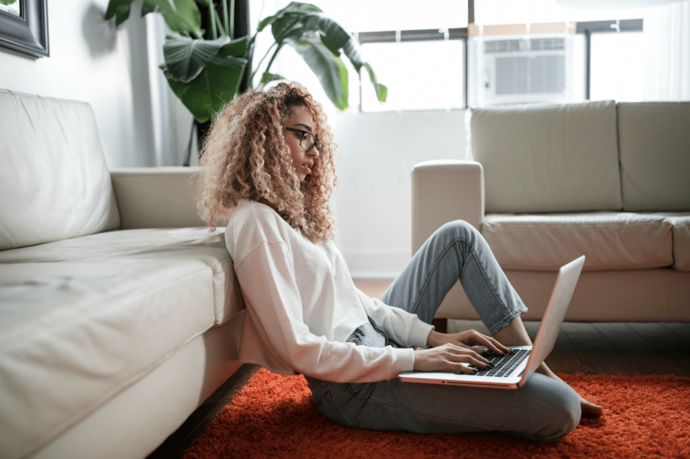 Young woman sitting on floor using laptop; image by ThoughtCatalog.com, via Unsplash.com.