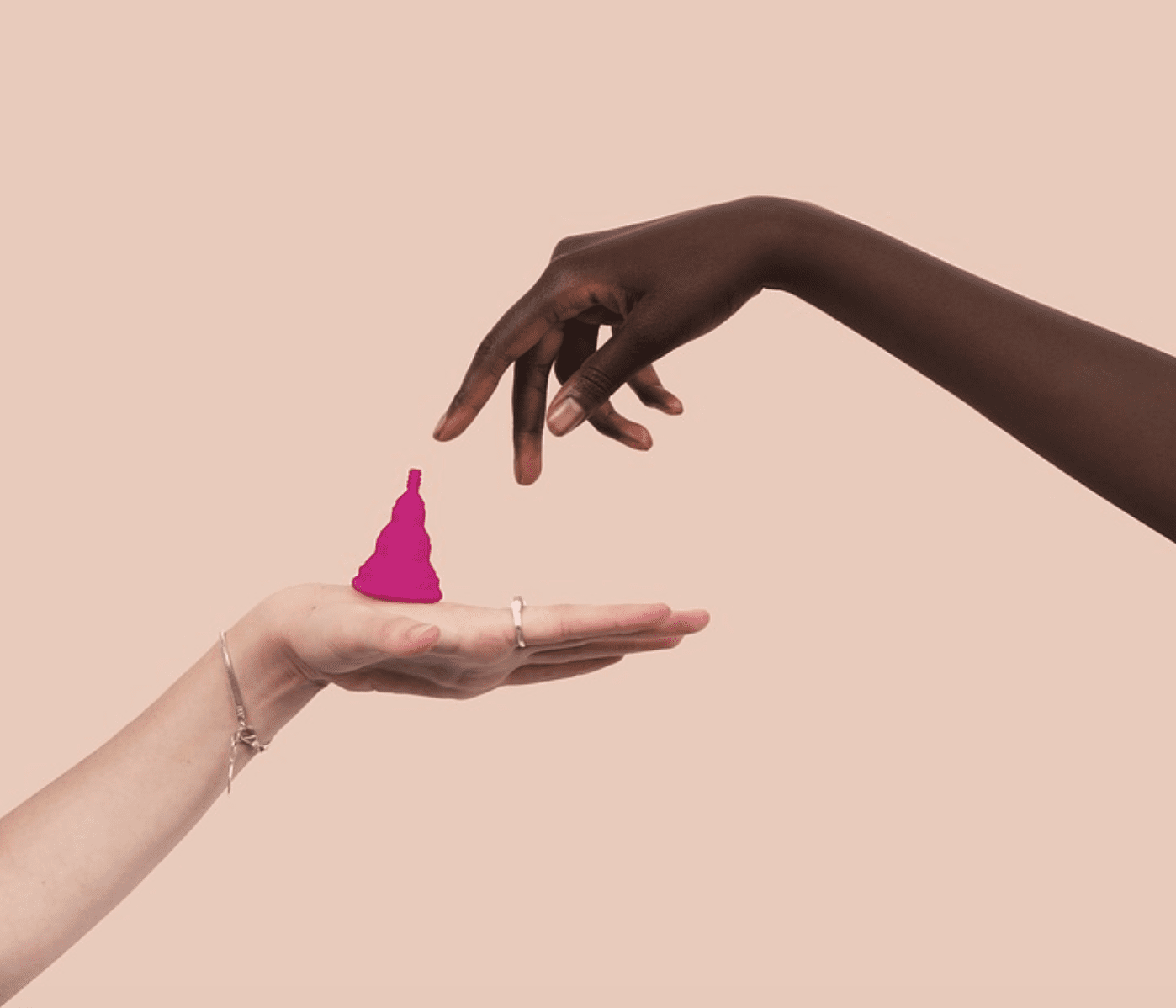 Two women’s hands, one balancing a menstrual cup; image by PatriciaMoraleda, via Pixabay.com.