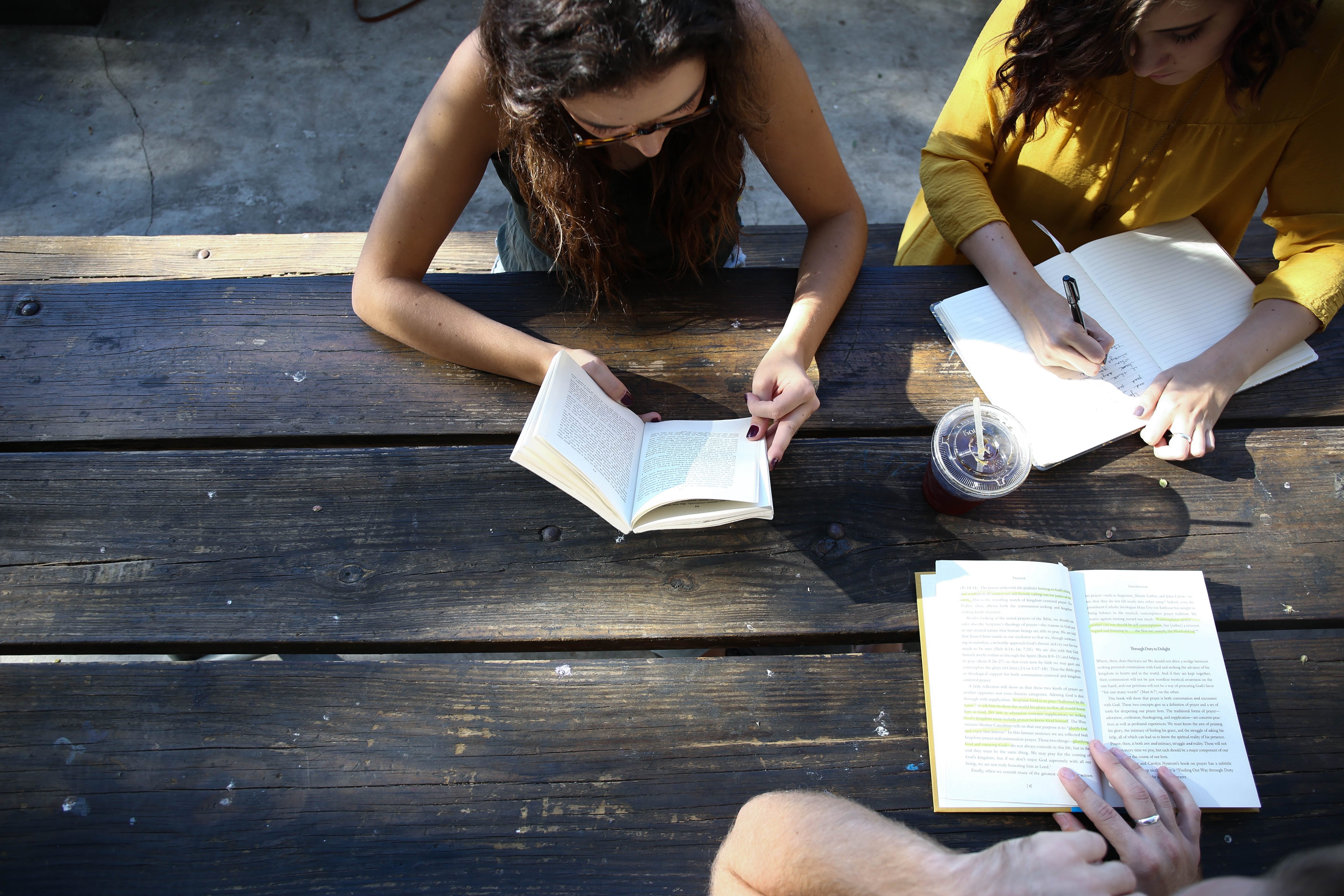 Three people studying at an outdoor table; image by Alexis Brown, via Unsplash.com.