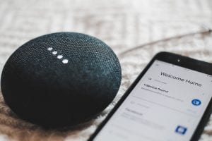 Turned-on charcoal Google Home Mini and smartphone; image by Bence Boros, via Unsplash.com.