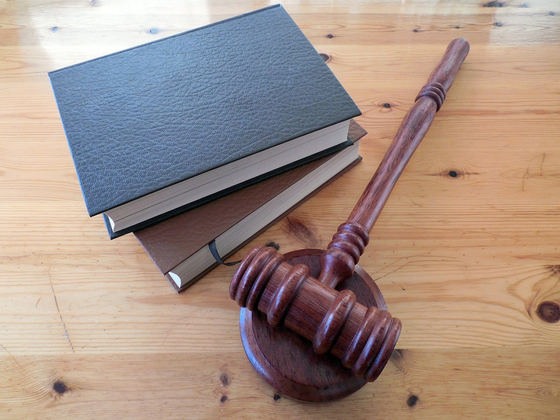 Gavel and two hardbound books on wooden table; image by Succo, via Pixabay.com.