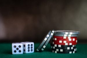 Two black and white dice and a small stack of multicolored chips; image by Heather Gill, via Unsplash.com.