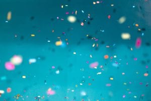 Colorful confetti falling down with a teal background; image by Jason Leung, via Unsplash.com.