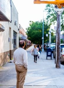 Man on sidewalk watching woman walk away with her bags; image by Jurien Huggins, via Unsplash.com.