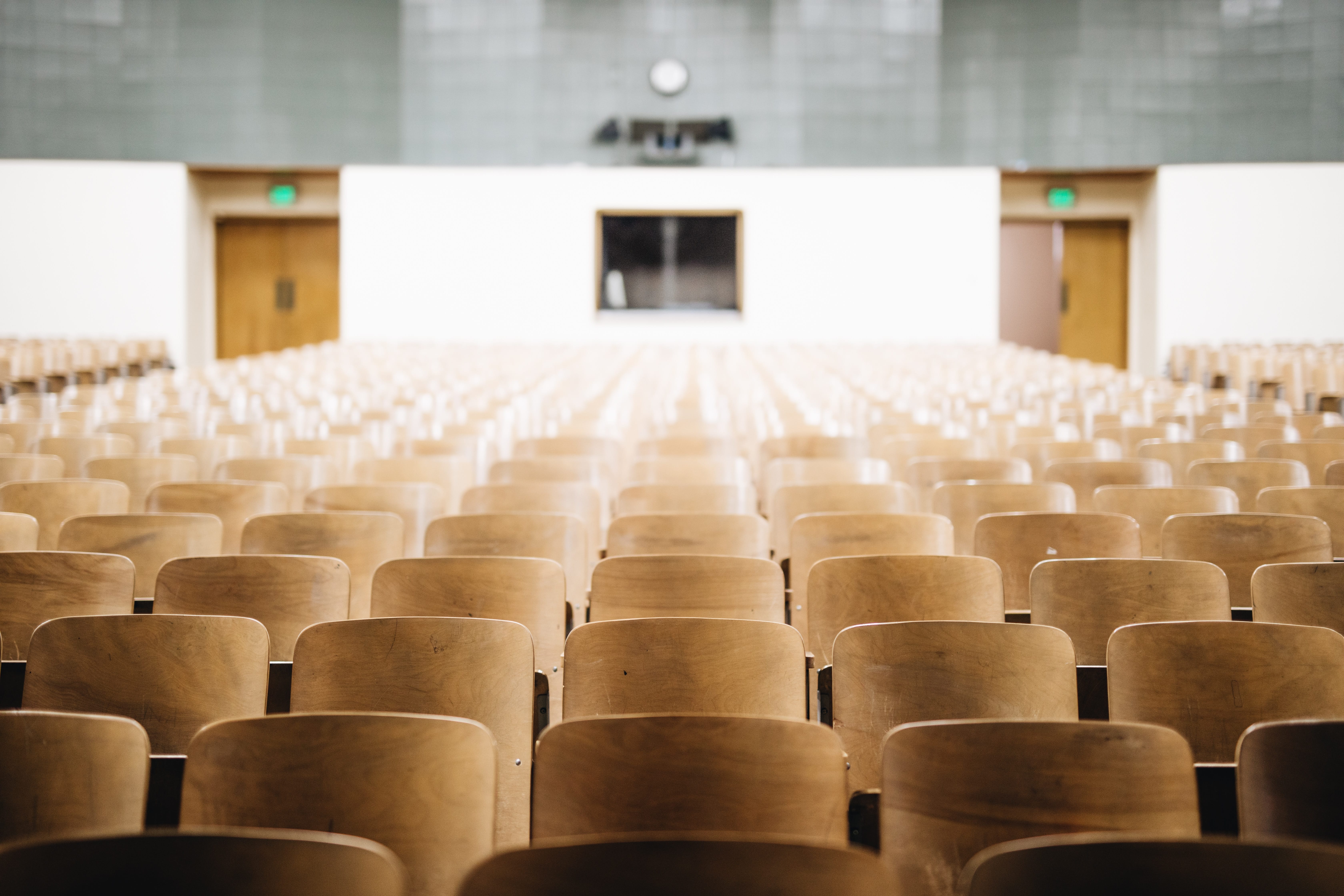 Rows of empty chairs in a classroom; image by Nathan Dumlao, via Unsplash.com.