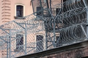 Gray barbwire on fence near building; image by Paweł Czerwiński, via Unsplash.com.