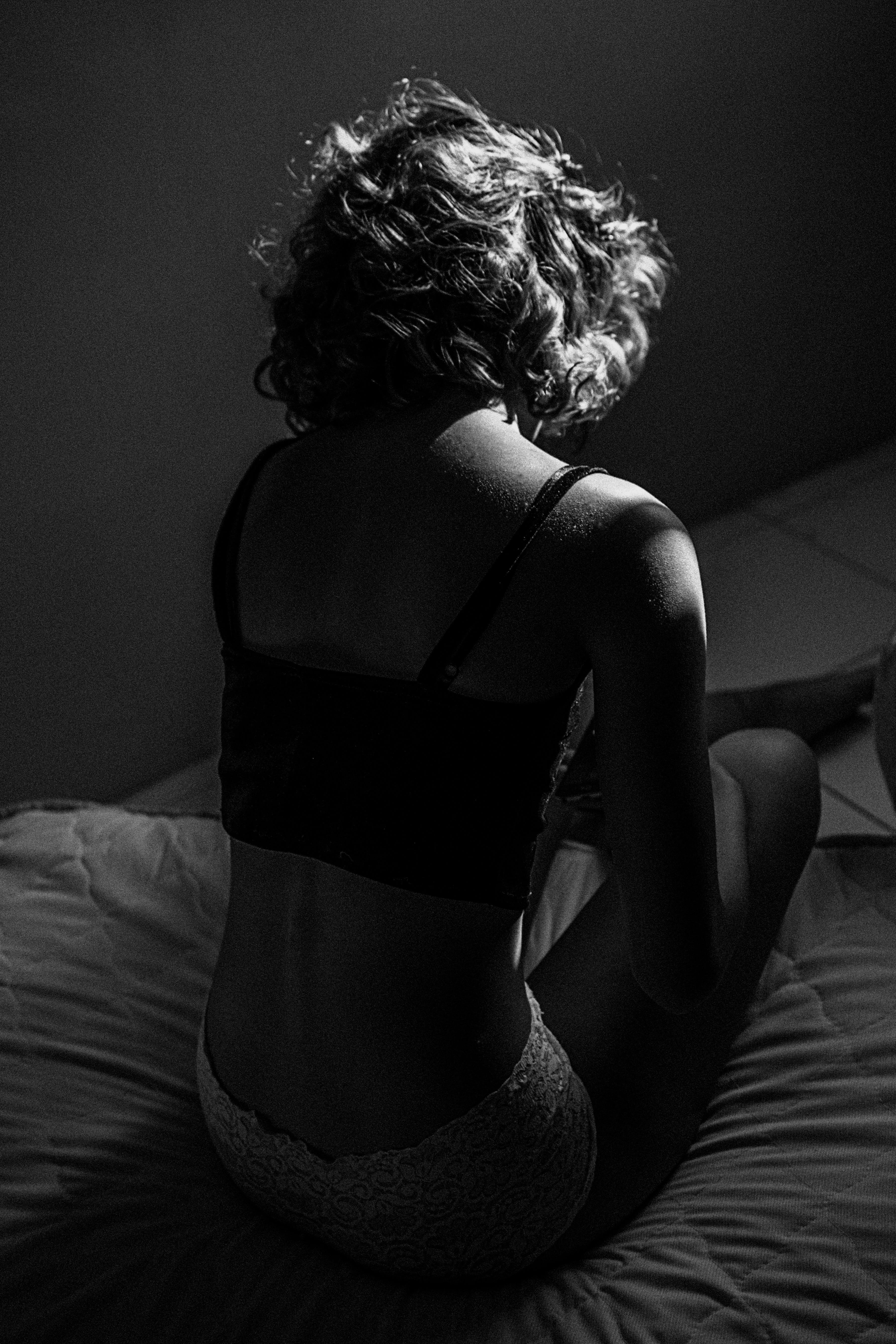 Gray scale photo of woman sitting on bed; image by Richard Jaimes, via Unsplash.com.