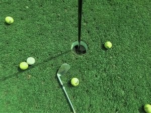 Six golf balls near hole and one golf club; image by TSG Pixels, via Unsplash.com.