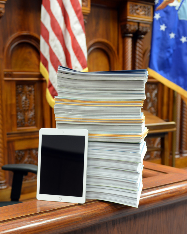 A tablet leans on a stack of legal documents.