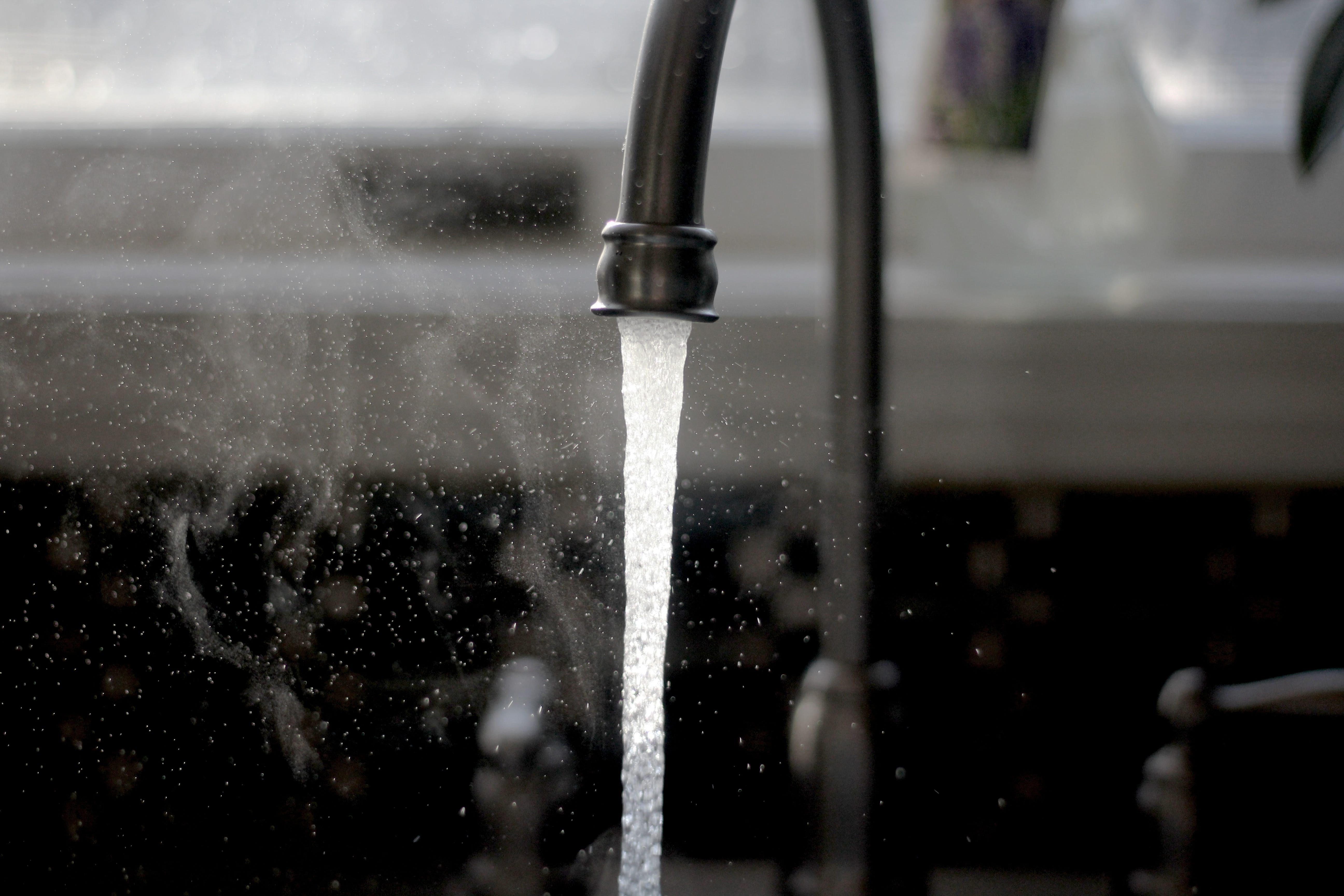 Greyscale photo of running faucet; image by Imani, via Unsplash.com.