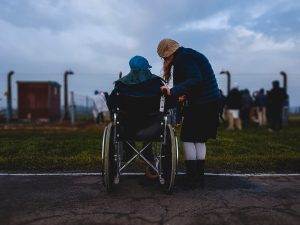 Woman standing near person in wheelchair near green grass field; image by Josh Appel, via Unsplash.com.