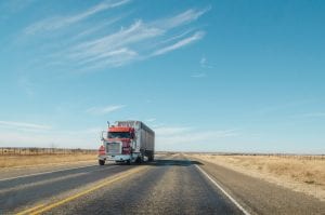 Red semi driving down the road; image by Matthew T. Rader, via Unsplash.com.