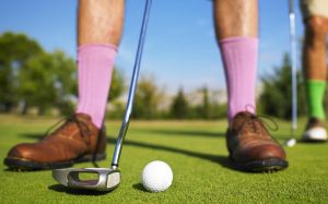 Man in lavender socks preparing golf shot; image by Morgan David de Lossy, via Unsplash.com.