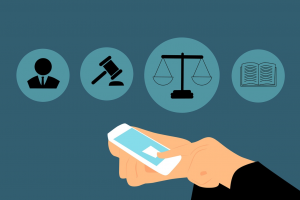 Graphic depicting lawyer holding smartphone, various legal symbols in the air before the the lawyer. Graphic by Mohamed Hassan, via Pixabay.com.