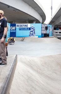 Skateboard ramp with banner saying “Redefine Possible,” showing wheelchair athletes. Image by Allie Smith, via Unsplash.com.