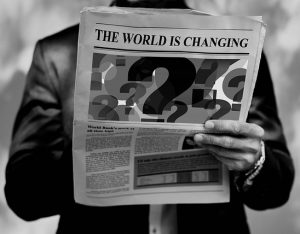 Black and white image of a man reading a newspaper.