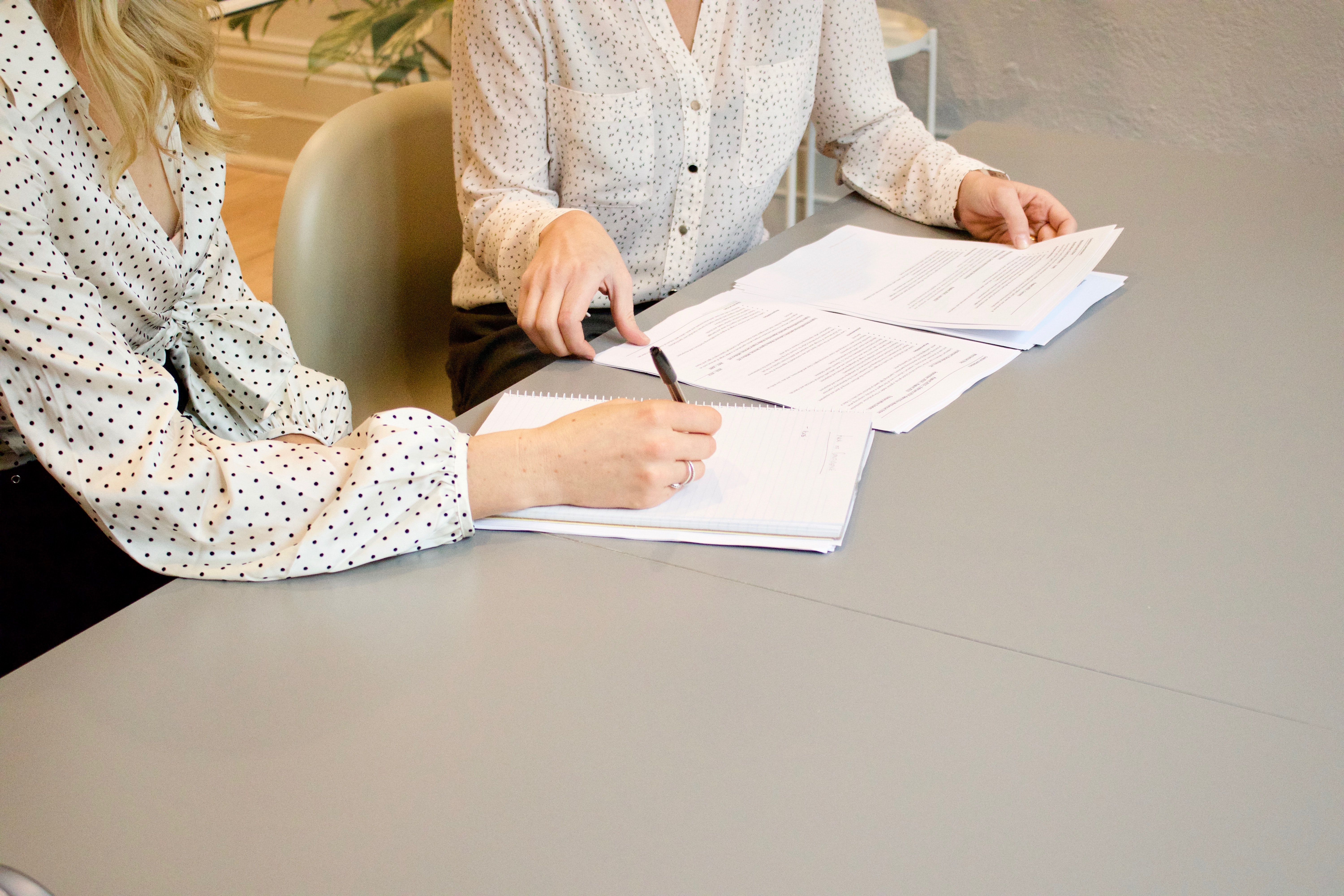 Two women reviewing paperwork; image by Freshh Connection, via Unsplash.com.