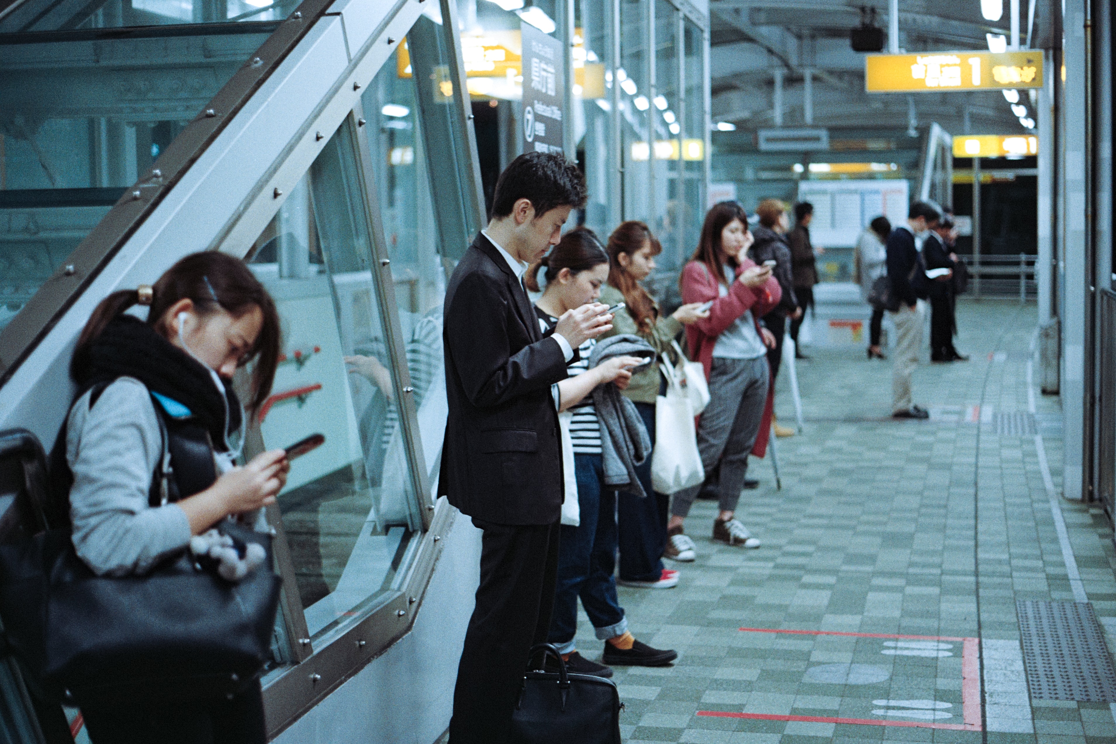 People on train platform using smartphones; image by Jens Johnsson, via Unsplash.com.