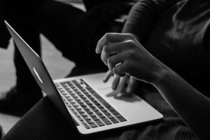 Grayscale photo of person using MacBook; image by Sergey Zolkin, via Unsplash.com.