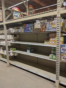 Empty store shelves in the paper goods section.