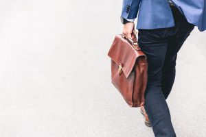 Man walking with brown leather briefcase; image by Marten Bjork, via Unsplash.com.