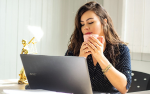 Lawyer having coffee while at laptop; image by Mateus Campos Felipe, via Unsplash.com.