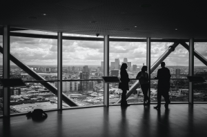 Three people meeting near a wall of windows; image by Charles Forerunner, via Unsplash.com.