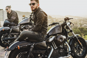 Two men sitting on parked motorcycles; image by Harley-Davidson, via Unsplash.com.