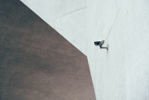 Camera mounted on wall at corner of building; image by Patrick Robert Doyle, via Unsplash.com.