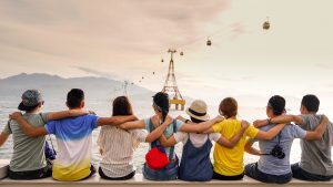 Group of people sitting on bench with arms around each other looking at water; image by Duy Pham, via Unsplash.com.