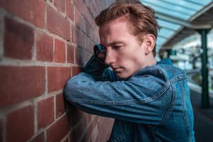 Teen boy in denim jacket leaning on brick building; image by Peter F. Wolf, via Unsplash.com.