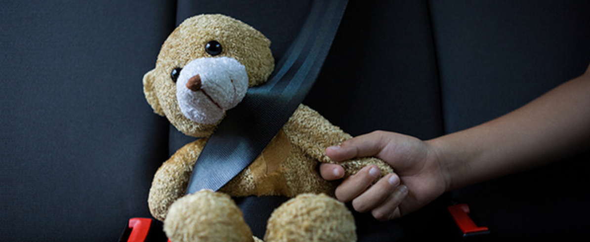 Teddy bear wearing a seatbelt, hand held by a child; image courtesy of Lex Machina.