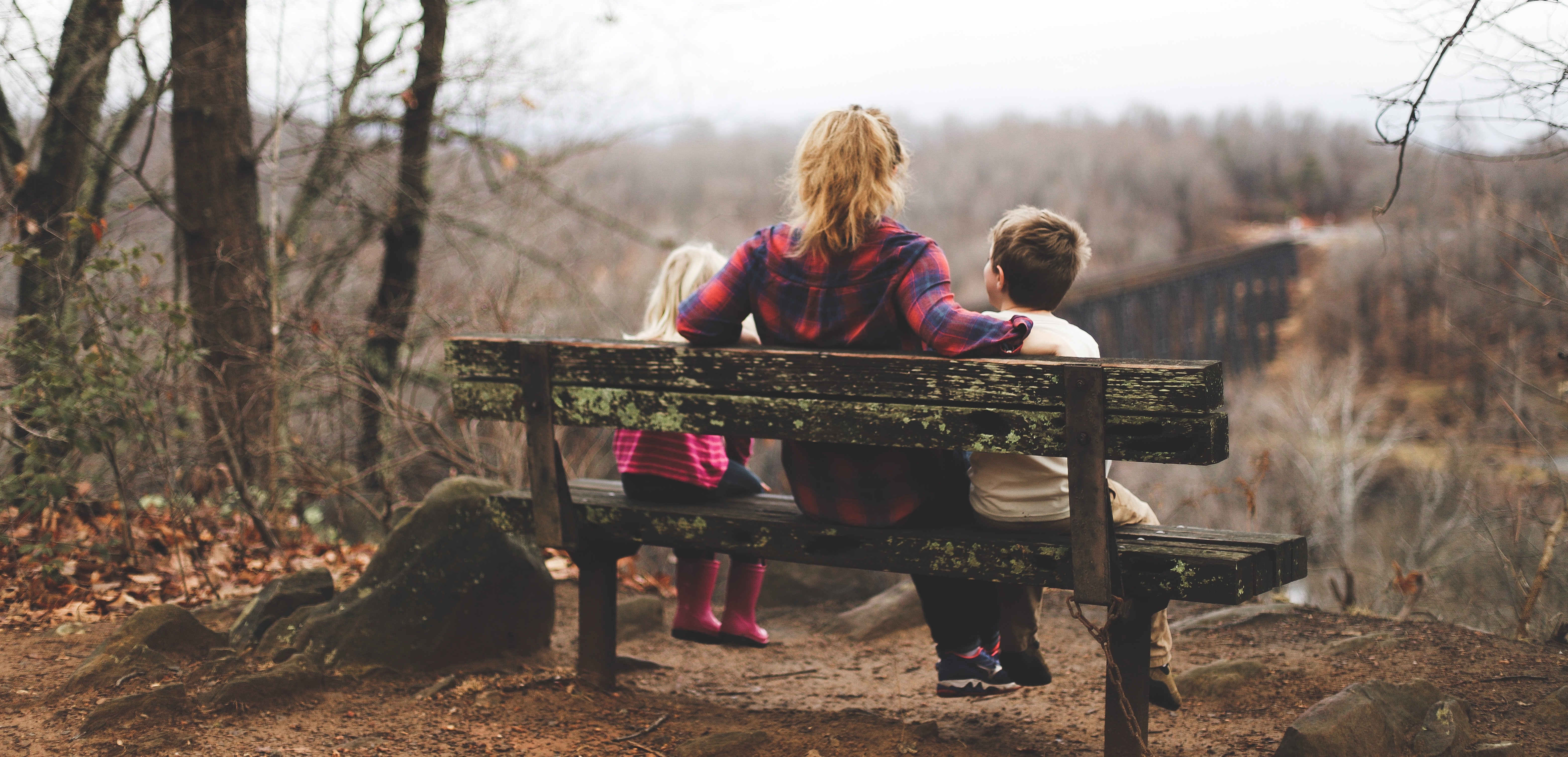 Woman and two children on a park bench; image by Benjamin Manley, via Unsplash.com.