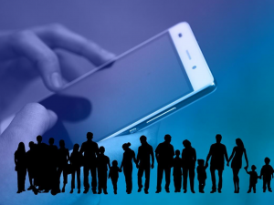 Silhouette of crowd against an oversized hand holding a smartphone; image by Geralt; via Pixabay.com.