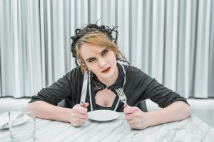 Angry woman at table with empty plate; image by Alex Iby, via Unsplash.com.