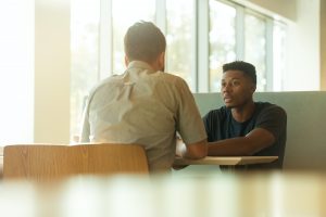 Two men sitting in booth talking; image by LinkedIn Sales Navigator, via Unsplash.com.