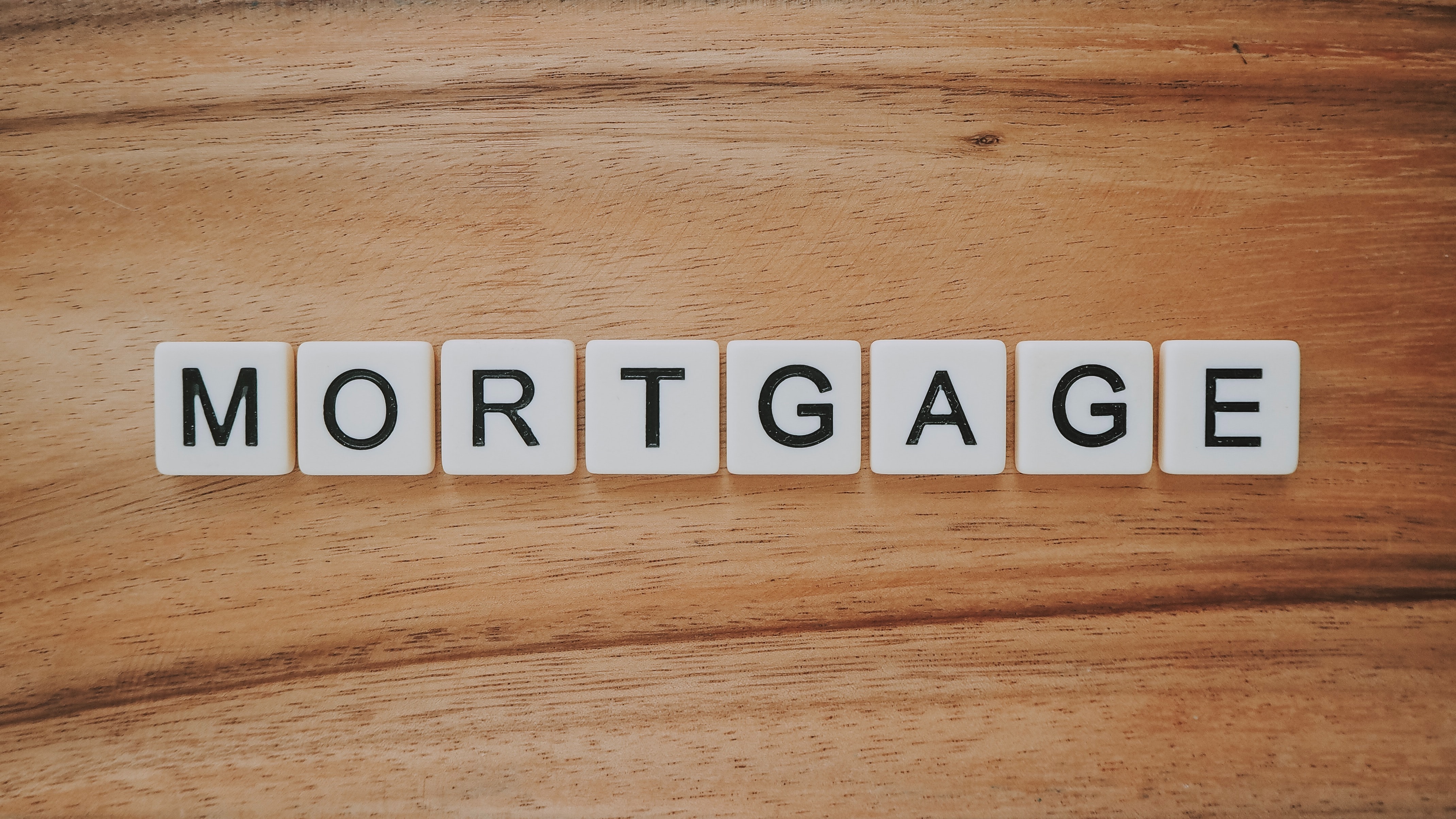 Scrabble tiles spelling out “Mortgage” on a light wooden background; image by Preconodo CA, via Unsplash.com.