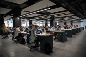 Open plan office space with rows of people working at long desks with no barriers.