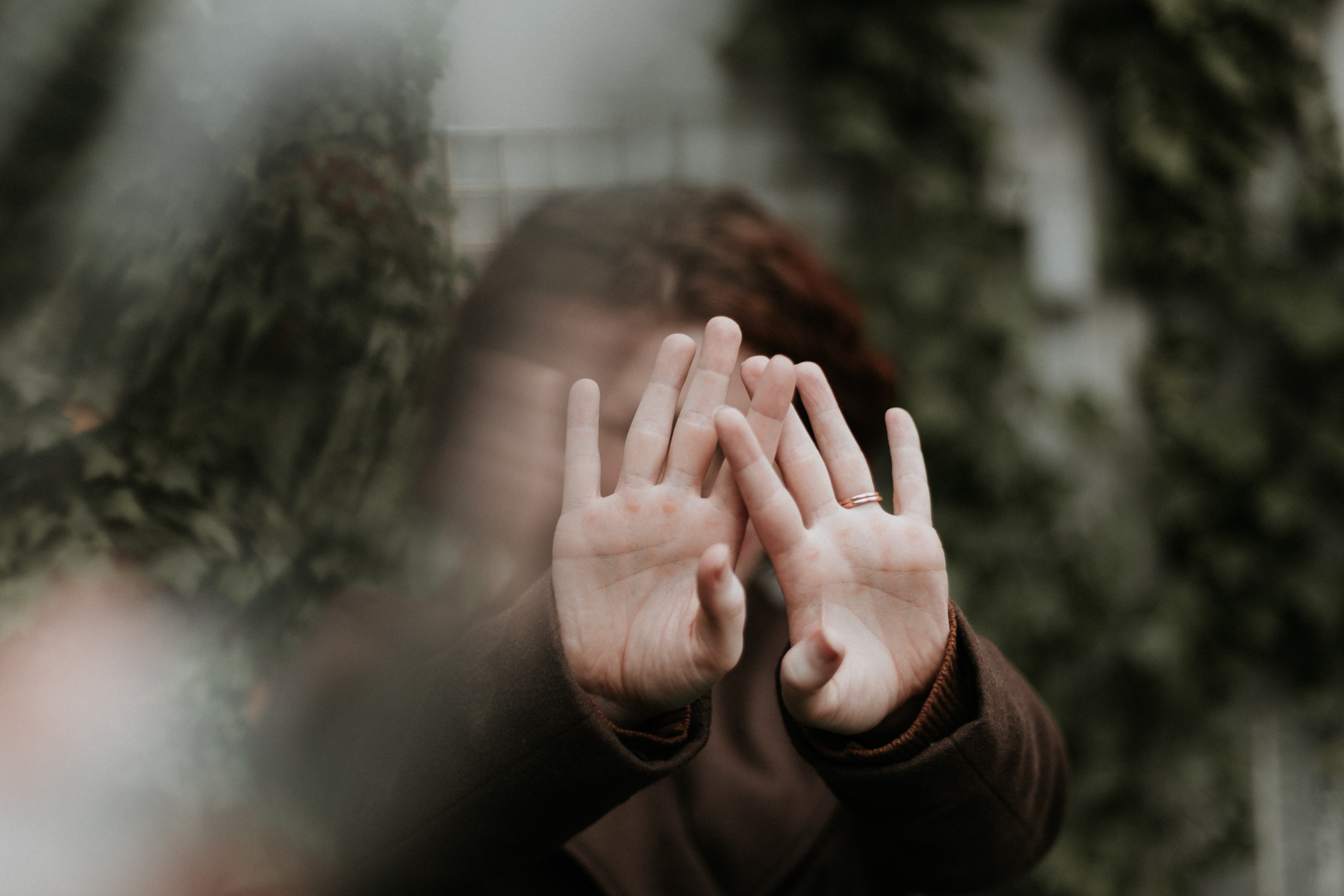 Woman holding her hands out, hiding her face; image by Priscilla Du Preez, via Unsplash.com.