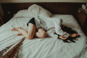 Woman lying on bed; image by Yuris Alhumaydy, via Unsplash.com.