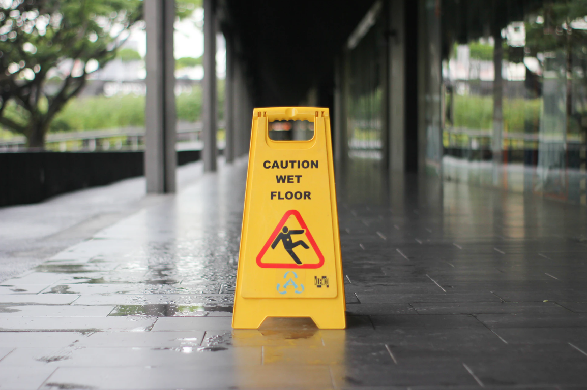 Yellow “Caution: Wet Floor” sign on wet floor; image by T.H. Chia, via Unsplash.com.